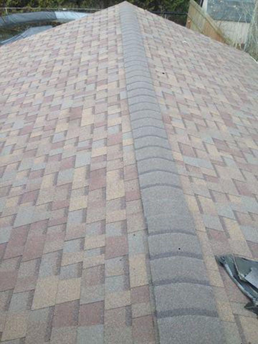 Brown and tan shingled roof with a dark gray ridge cap, viewed from above
