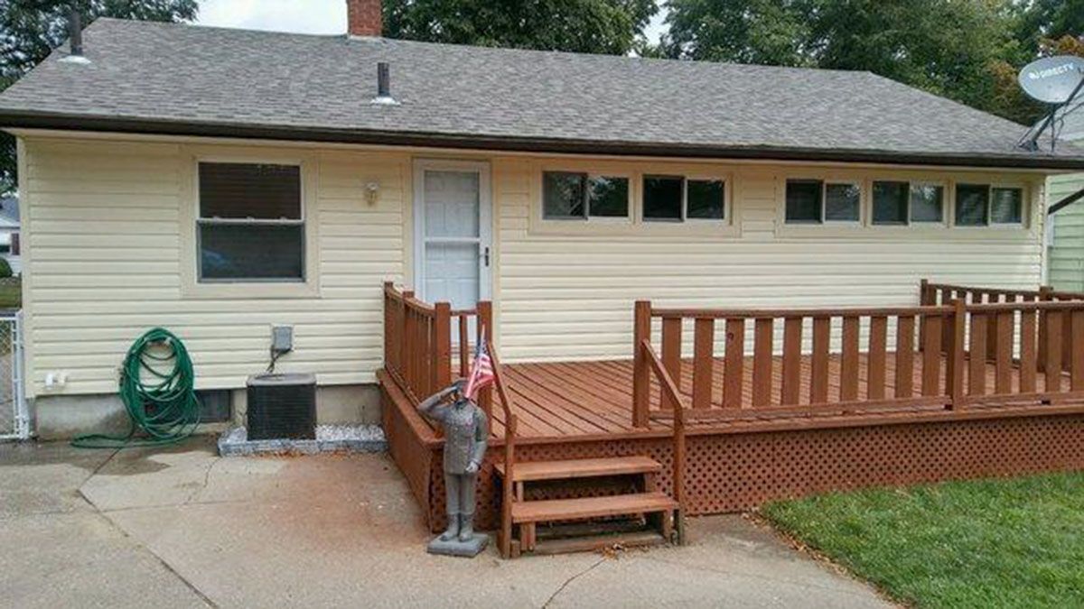 Back exterior of a beige house with a brown deck, windows, and door
