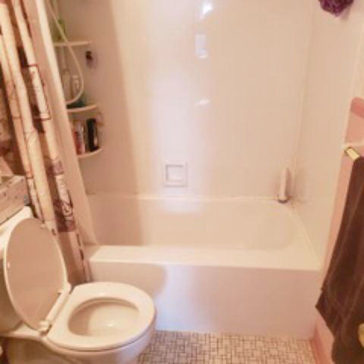 A small bathroom with a white tub, toilet, and a shower curtain