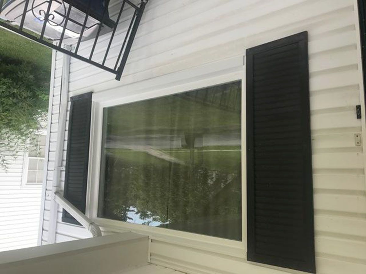 Window with black shutters on a white house exterior