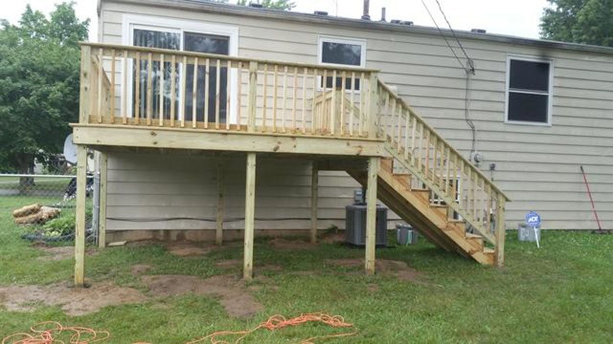 A wooden deck with stairs attached to the side of a beige house