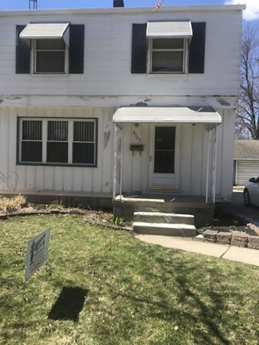 White two-story house with front porch, windows, and awnings