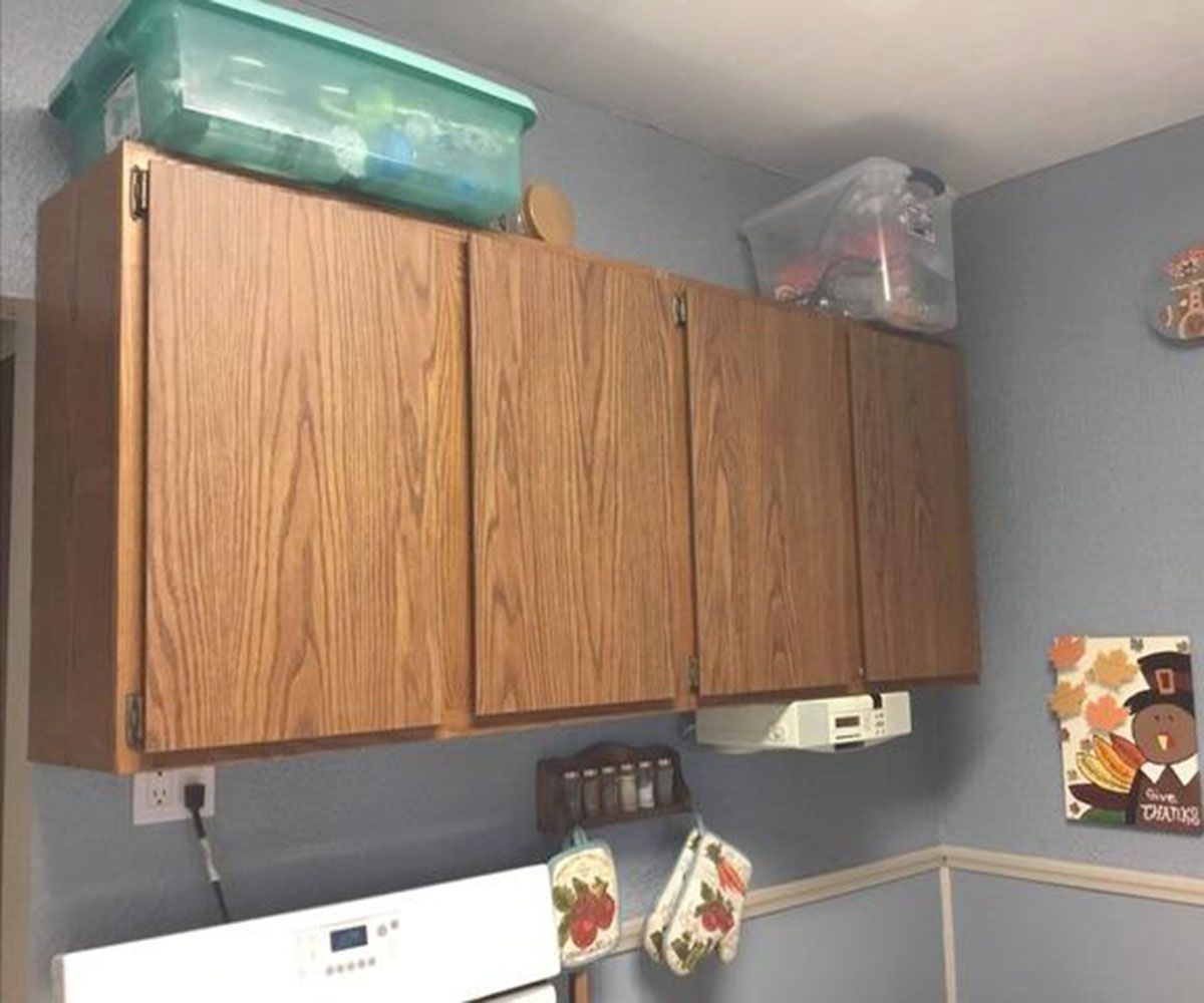 Wooden kitchen cabinets, containers on top, over a stove