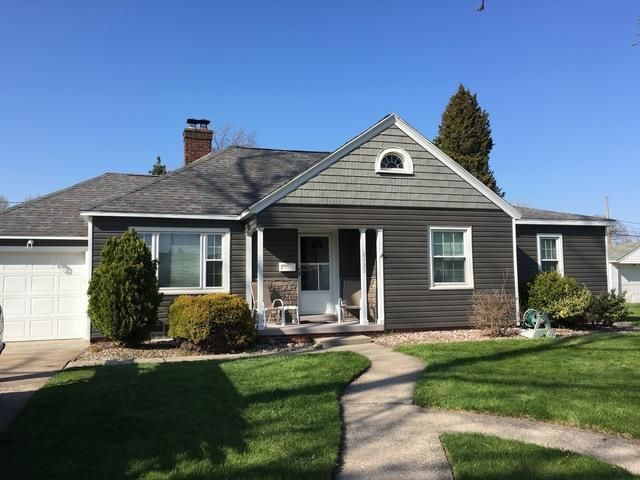 Gray house with dark siding, white trim, and a curved walkway on a sunny day.