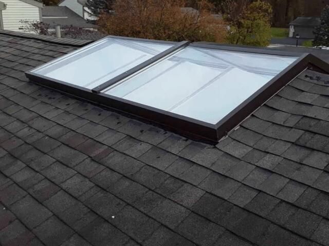 Two rectangular skylights on a dark shingle roof.