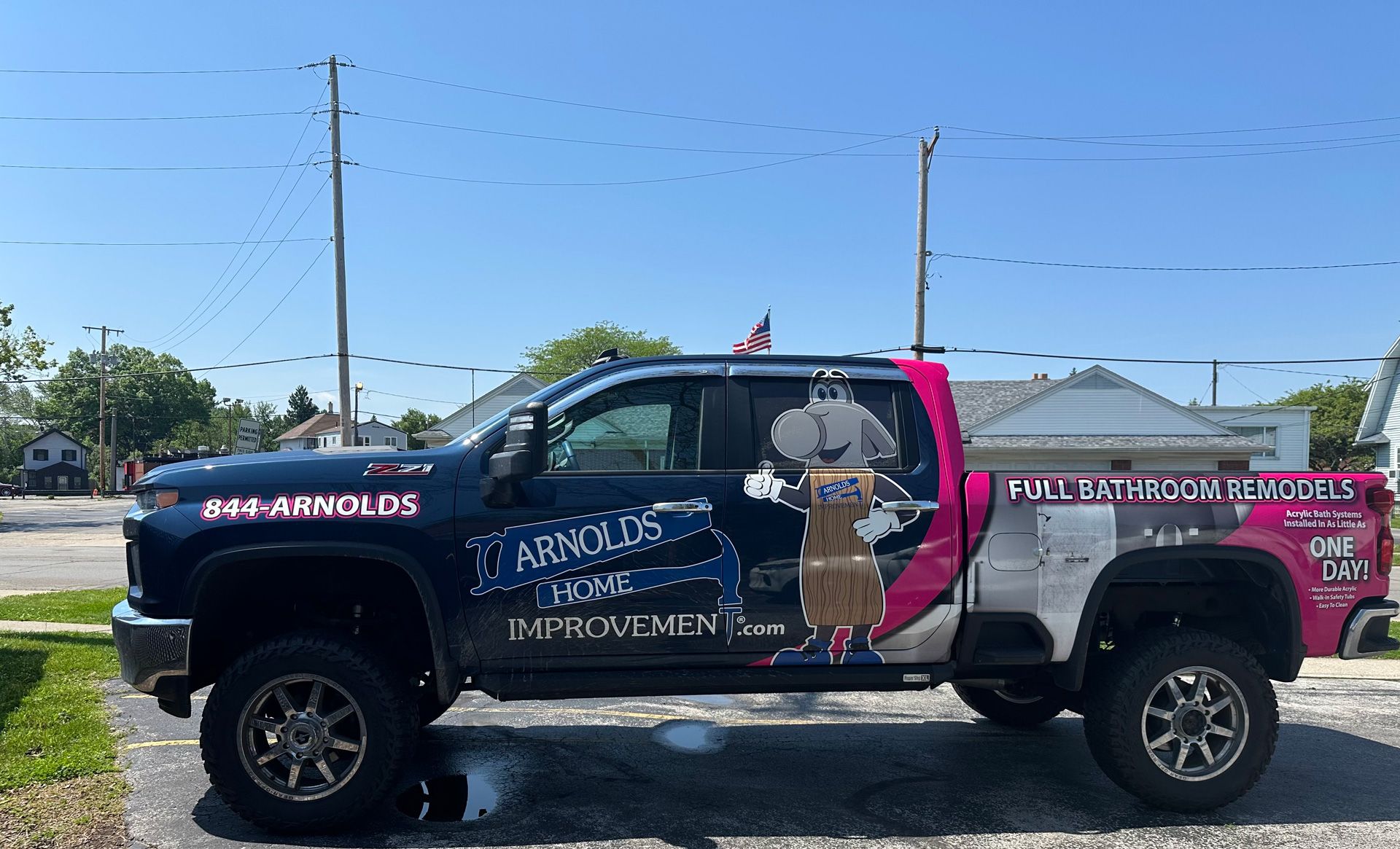 Decorated pickup truck with graphics and text parked outdoors under a bright blue sky