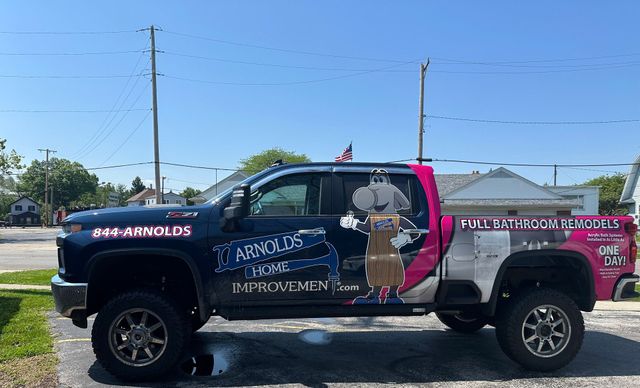Custom black-and-pink pickup truck with church branding parked outdoors on a sunny day