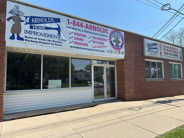 Arnold's Interior Improvement storefront with large windows, red brick facade, and roadside sign.