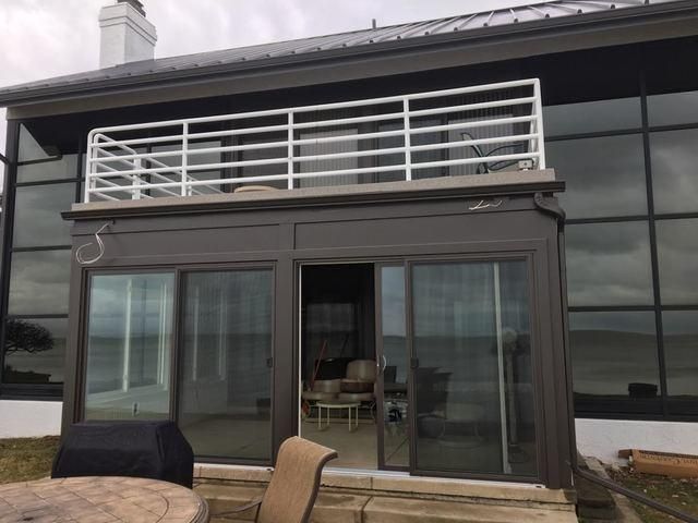 Modern house patio with large sliding glass doors and a white-railed balcony above