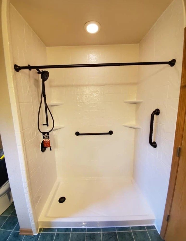 Accessible shower stall with grab bars, handheld shower, and bench shelf in a tiled bathroom