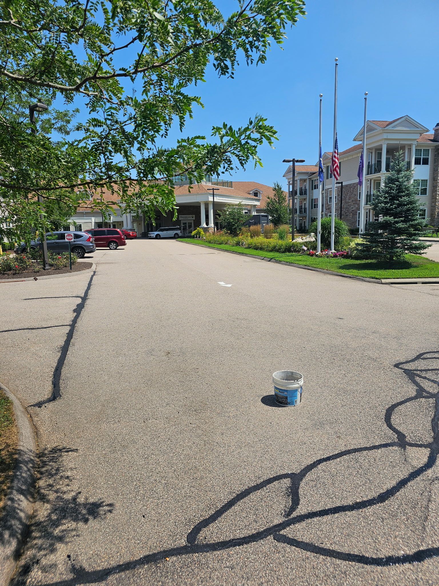 A gravel driveway leading toward a building entrance with a small paint bucket sitting on the ground.