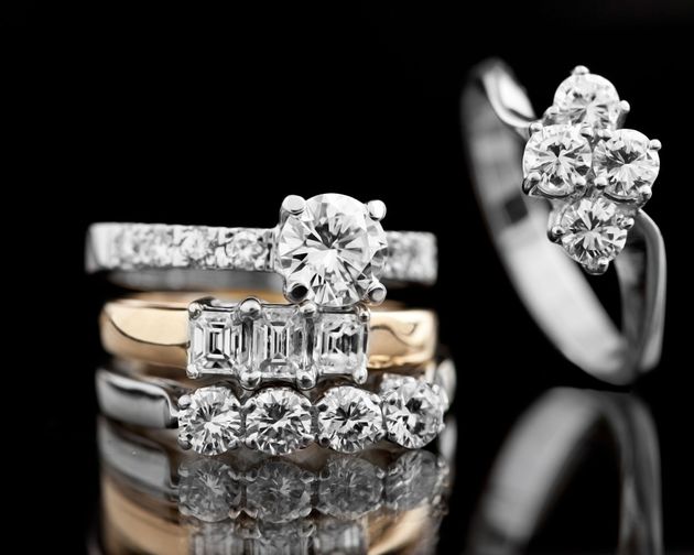 Diamond rings stacked on a reflective surface against a black background.