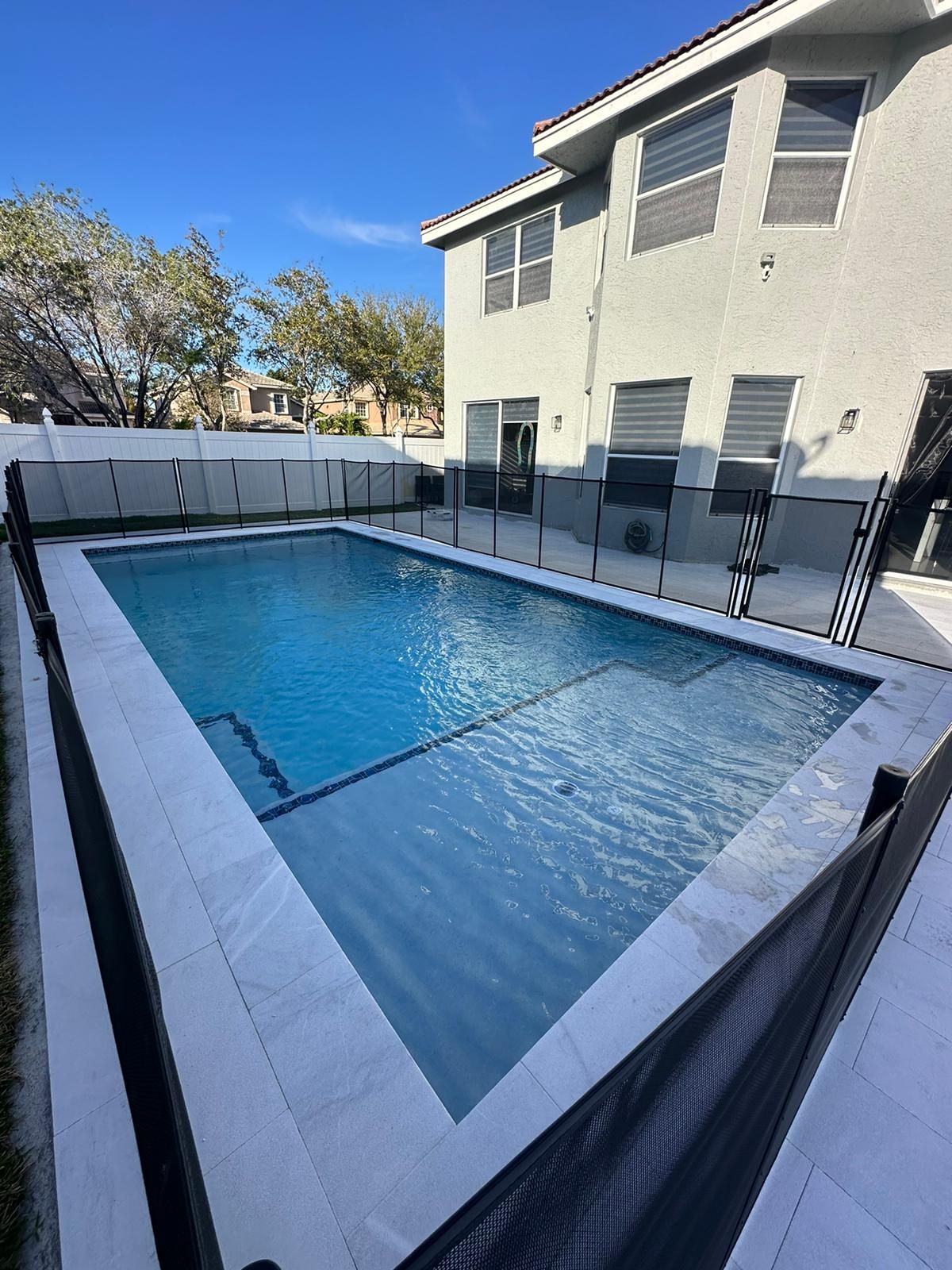 A large swimming pool is in the backyard of a house.