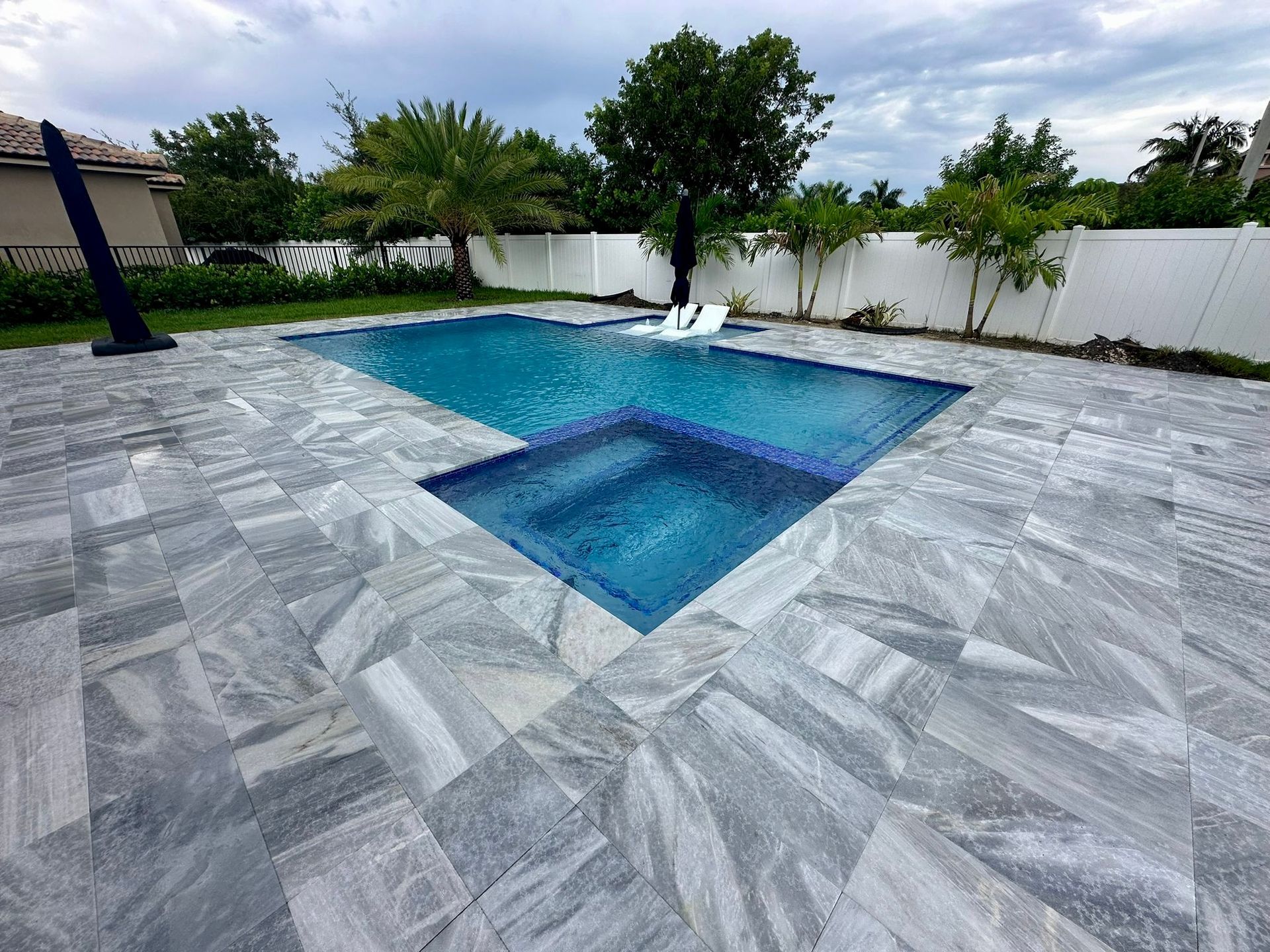 A large swimming pool is surrounded by a tiled patio.