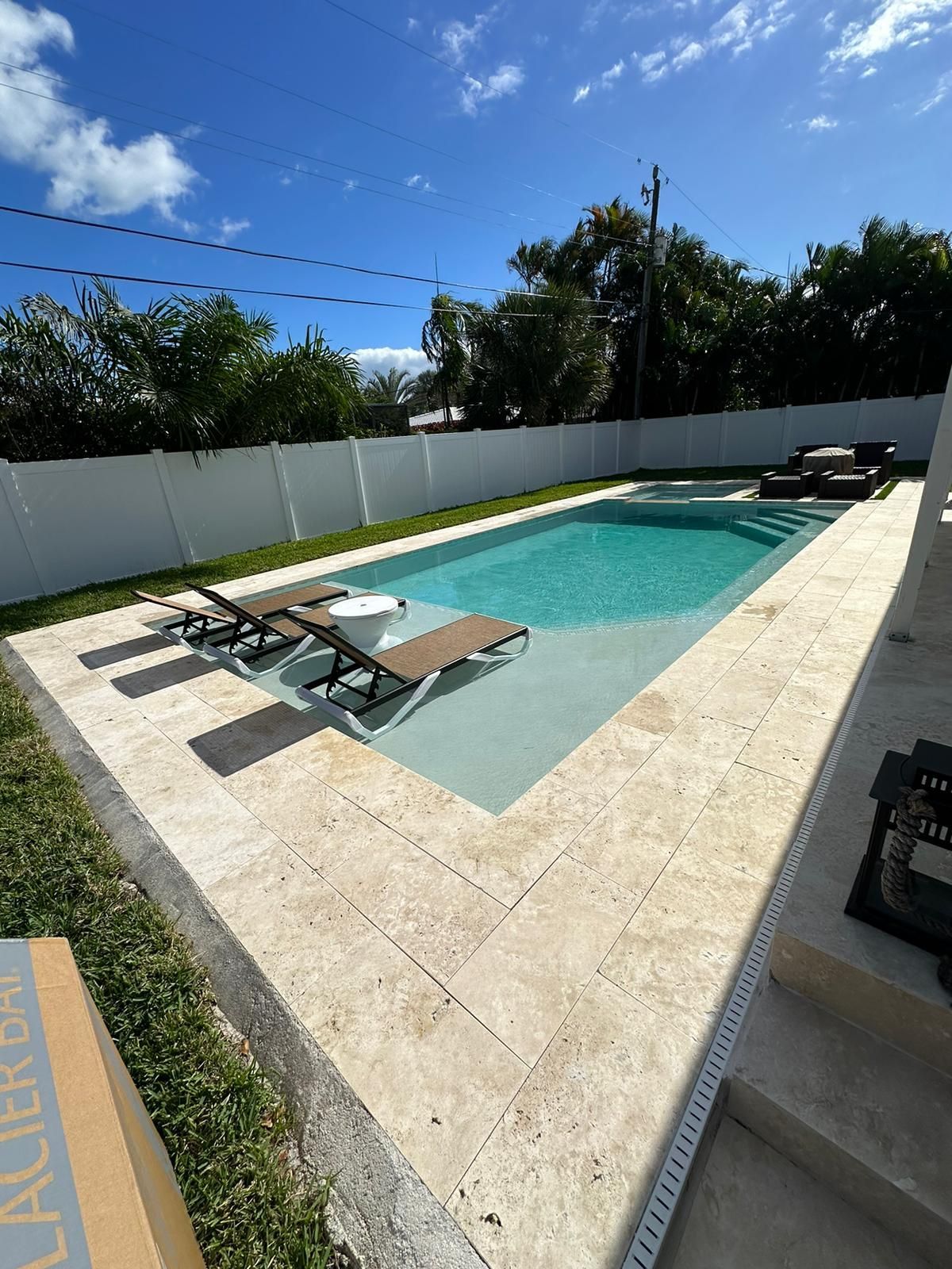 A large swimming pool with chairs around it in a backyard.