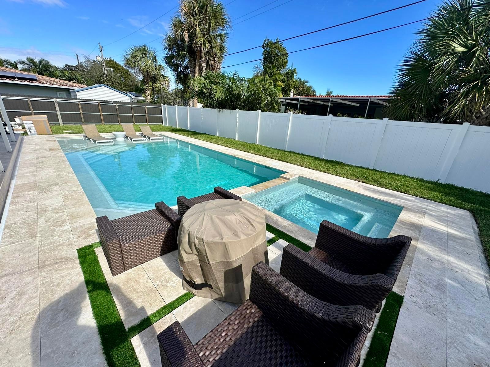A large swimming pool surrounded by chairs and a table