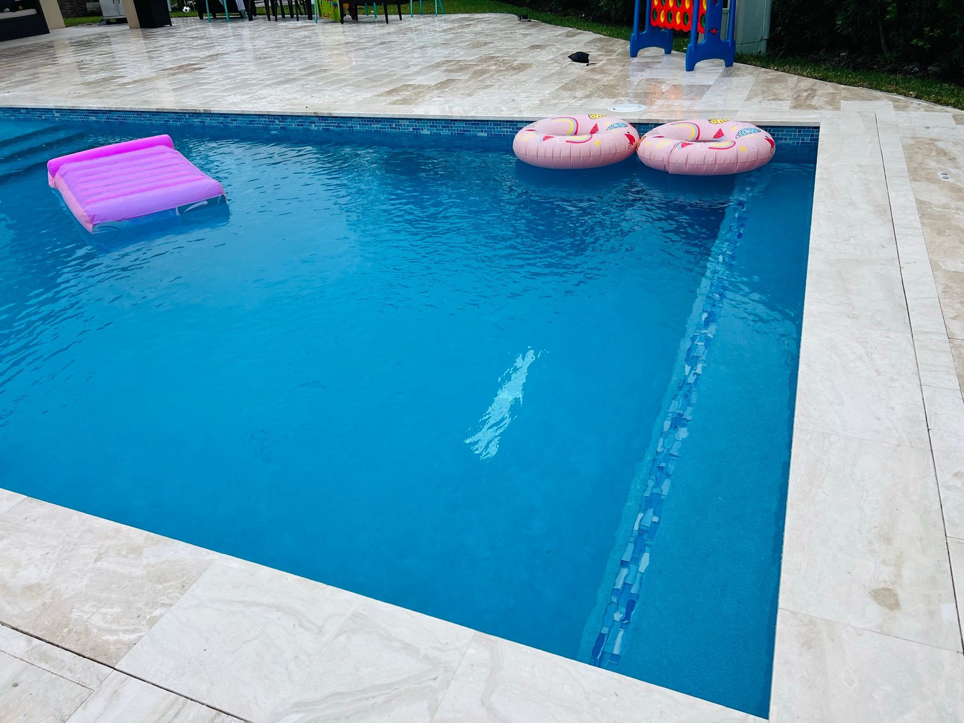 A large swimming pool with two pink floats in it.