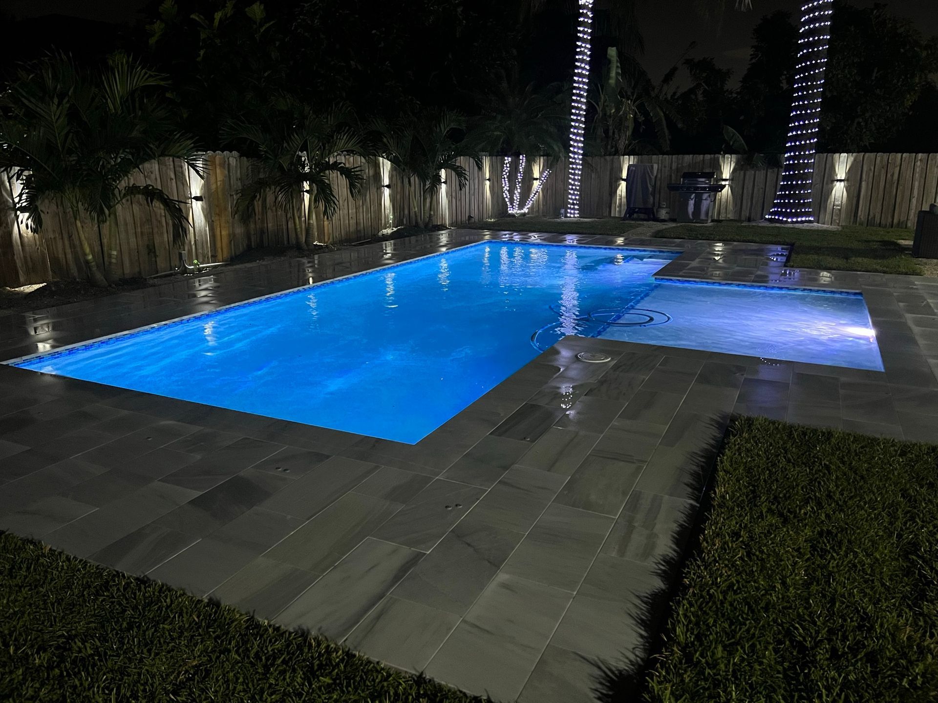 A large swimming pool is lit up at night.