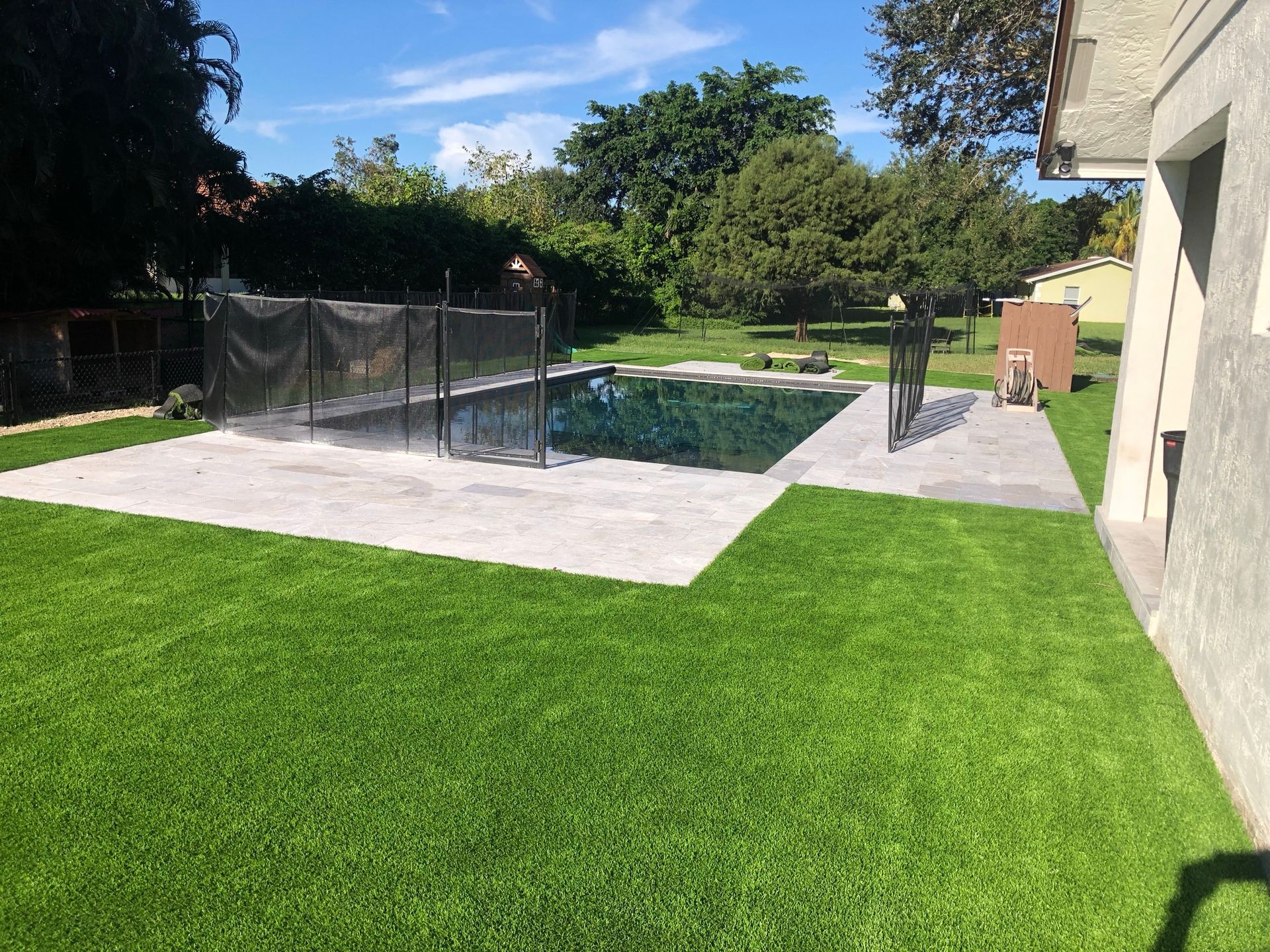 A large swimming pool is surrounded by a lush green lawn.