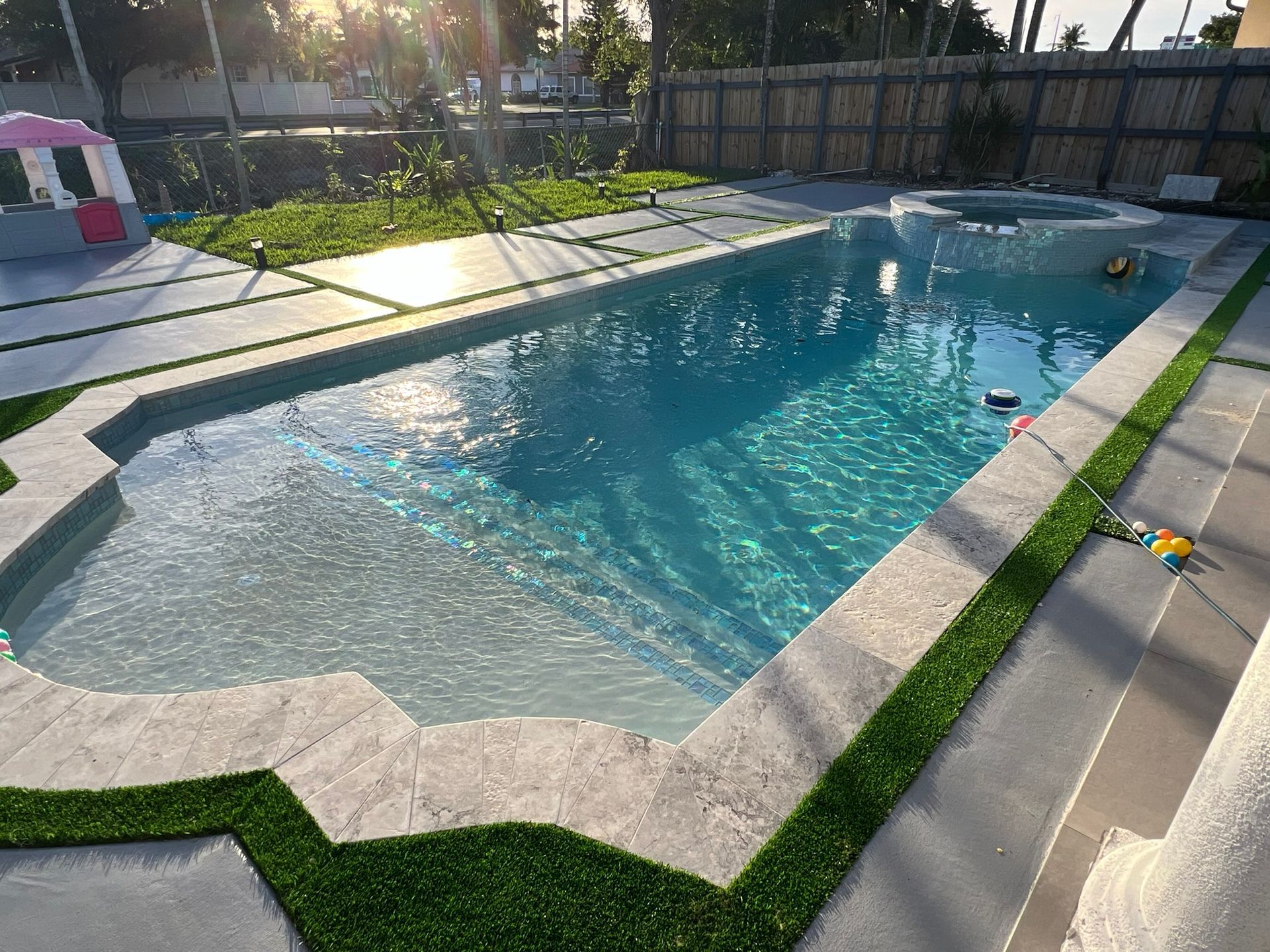 A large swimming pool surrounded by grass and a fence.