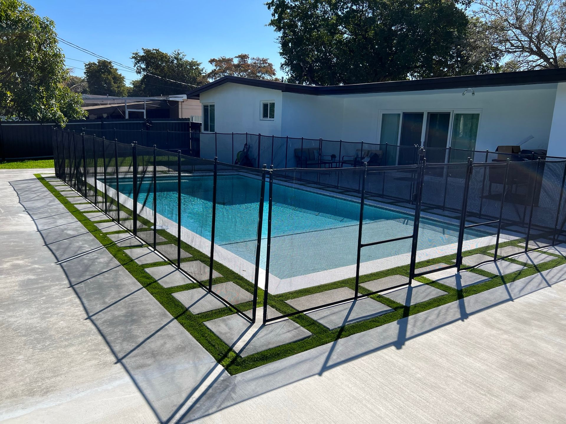 A swimming pool with a fence around it and a house in the background.