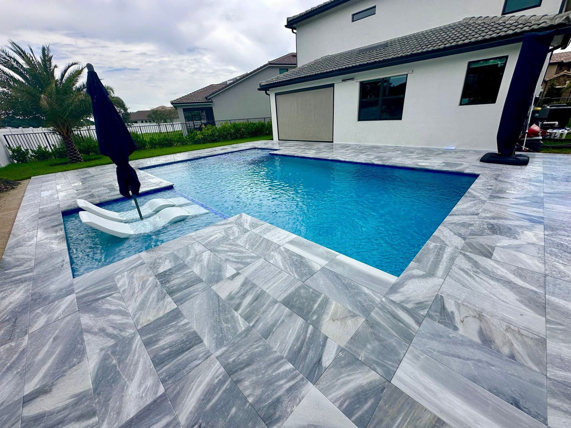 There is a large swimming pool in the backyard of a house.
