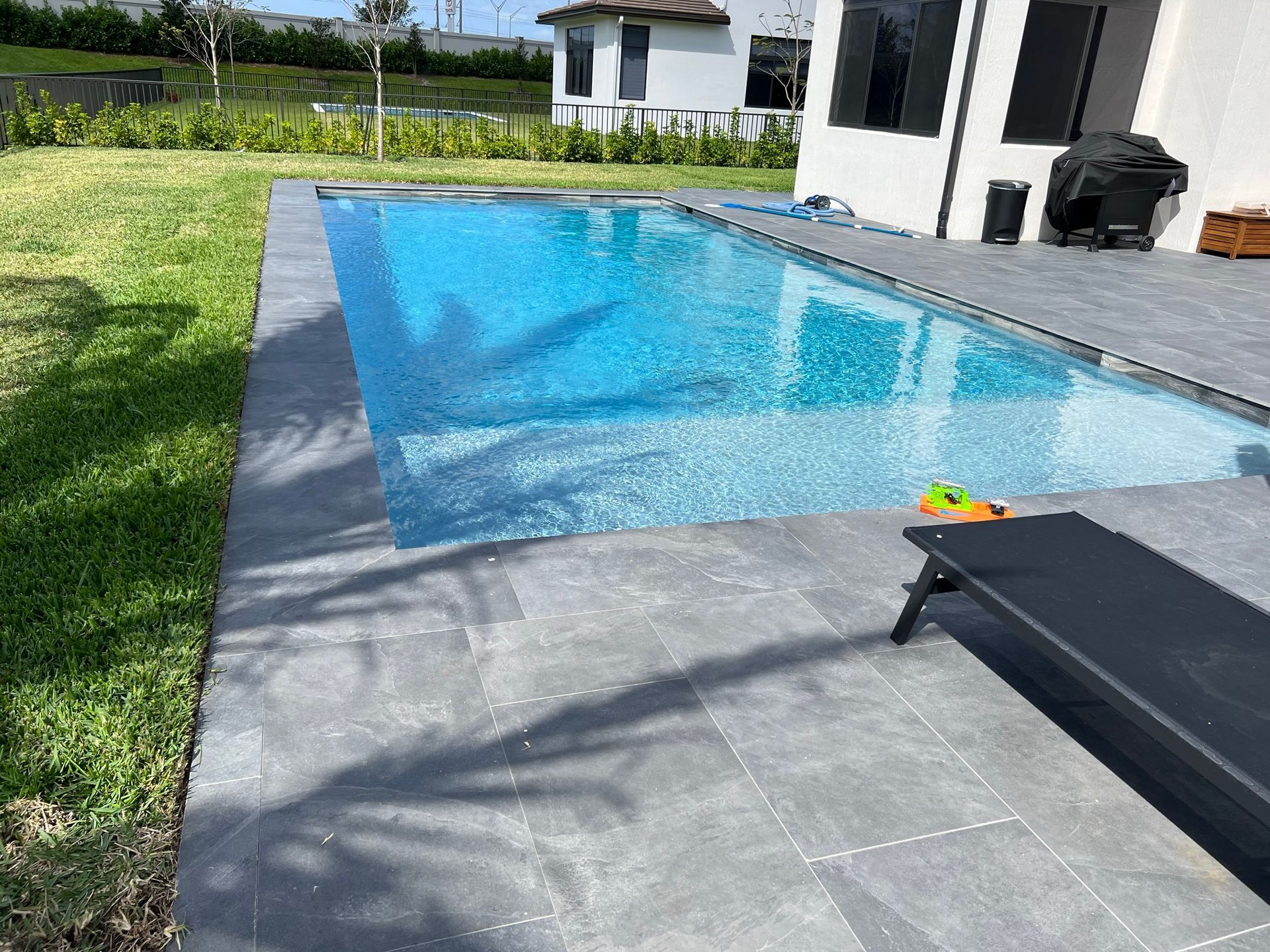 There is a large swimming pool in the backyard of a house.