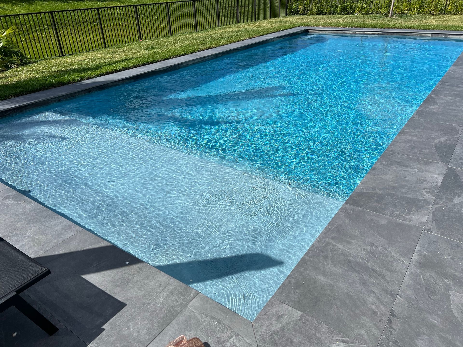 A person is standing next to a large swimming pool.