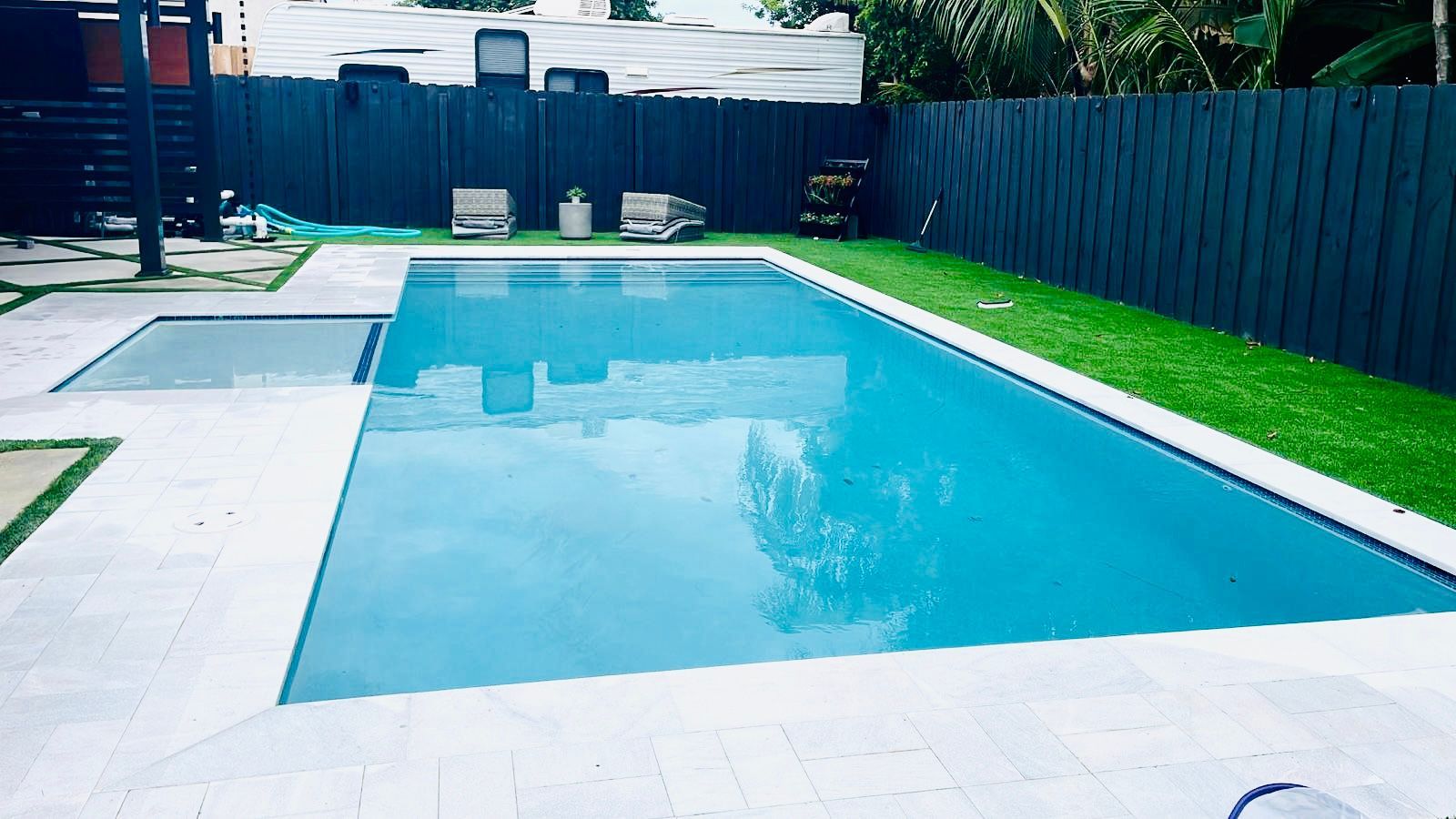 A large swimming pool in a backyard with a black fence.