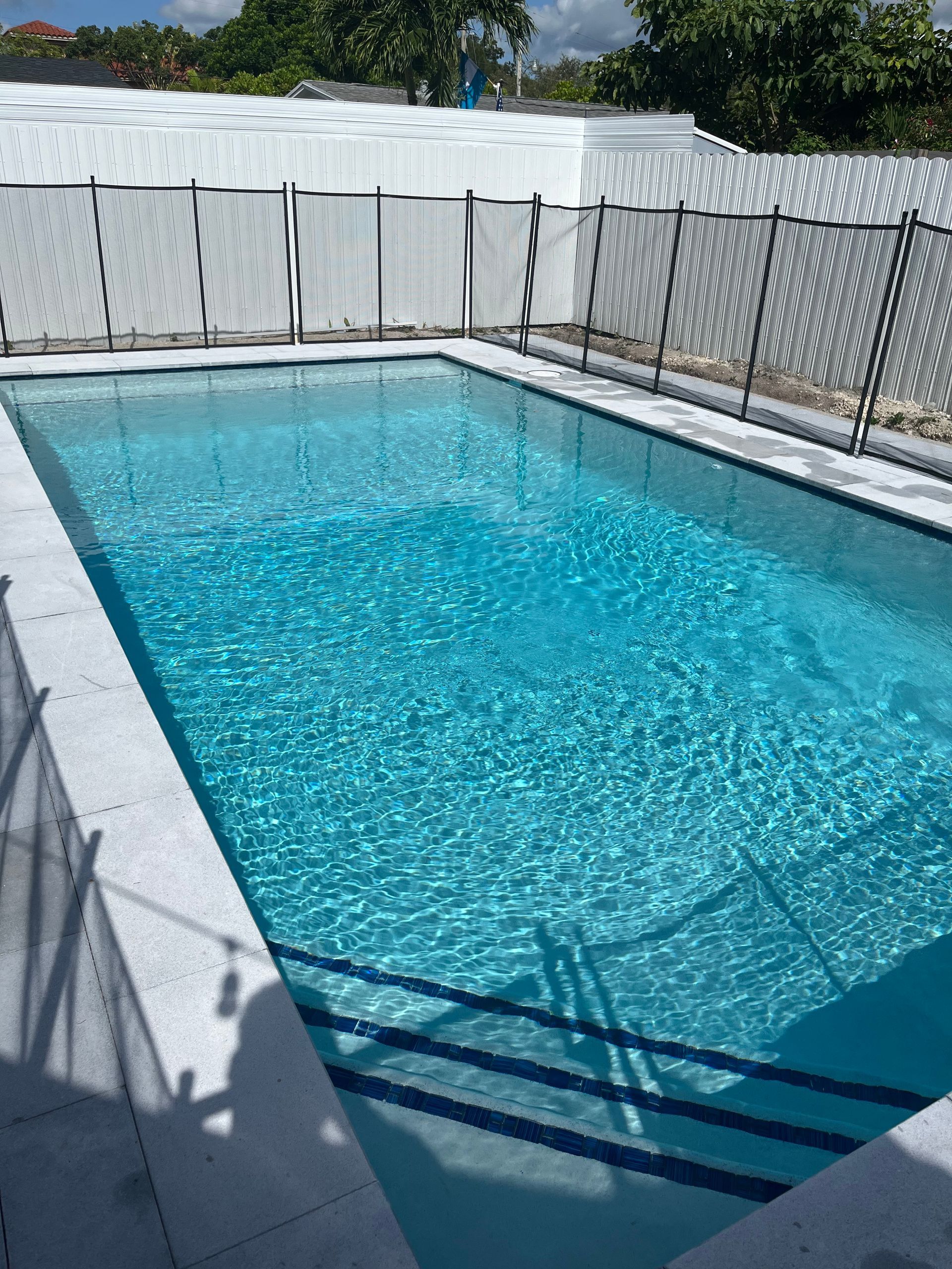 A large swimming pool with a white fence around it
