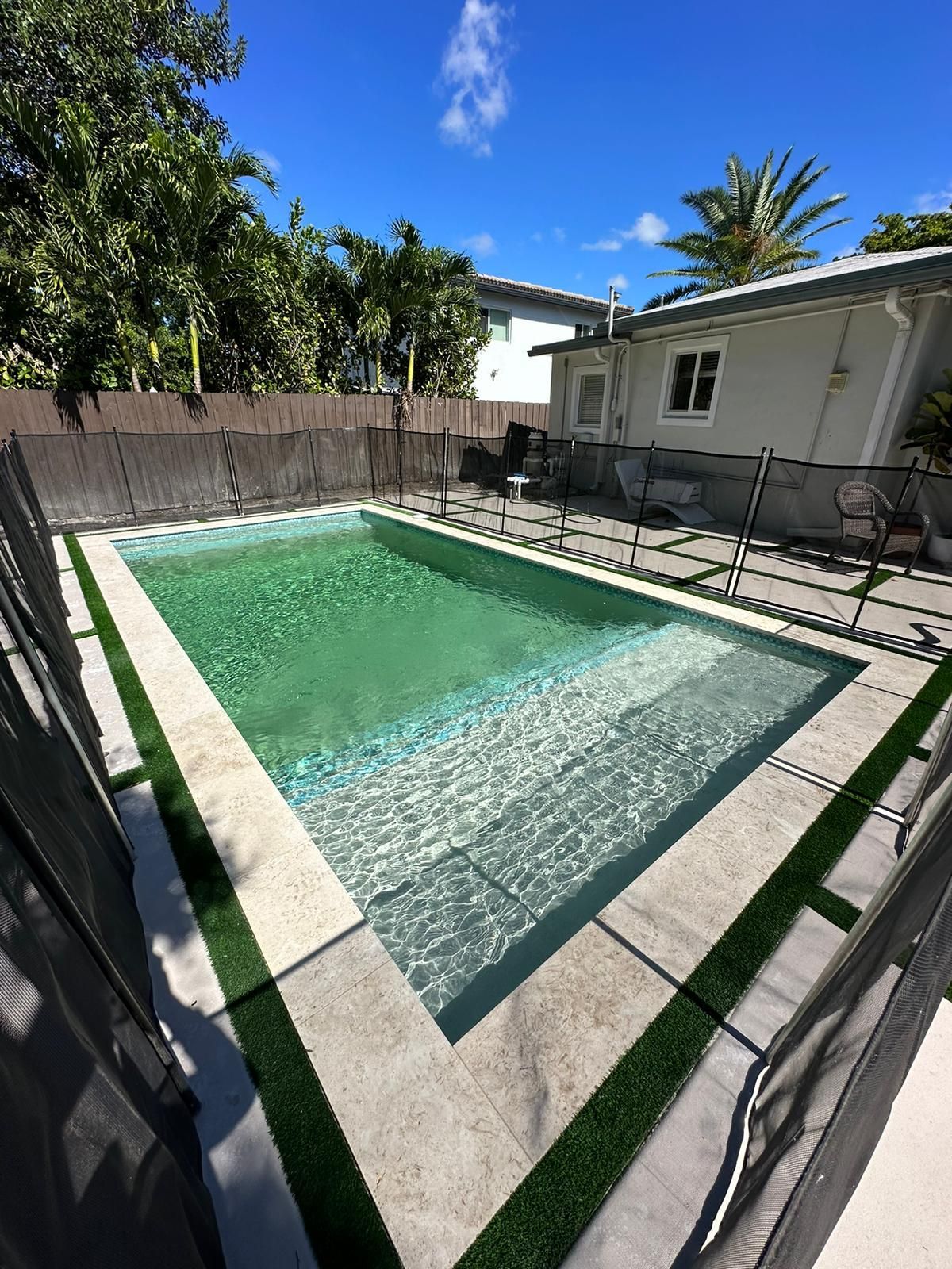 There is a large swimming pool in the backyard of a house.