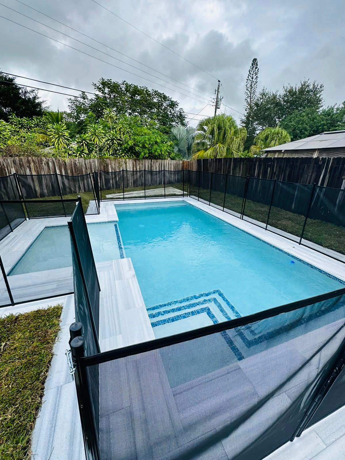 A large swimming pool surrounded by a fence in a backyard.