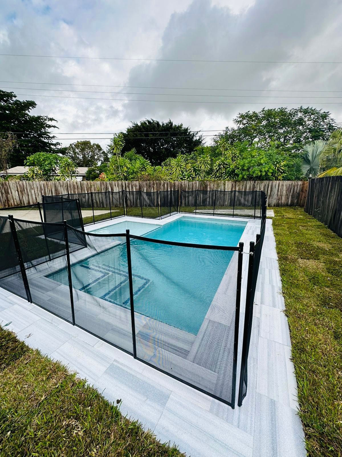 A large swimming pool surrounded by a fence in a backyard.