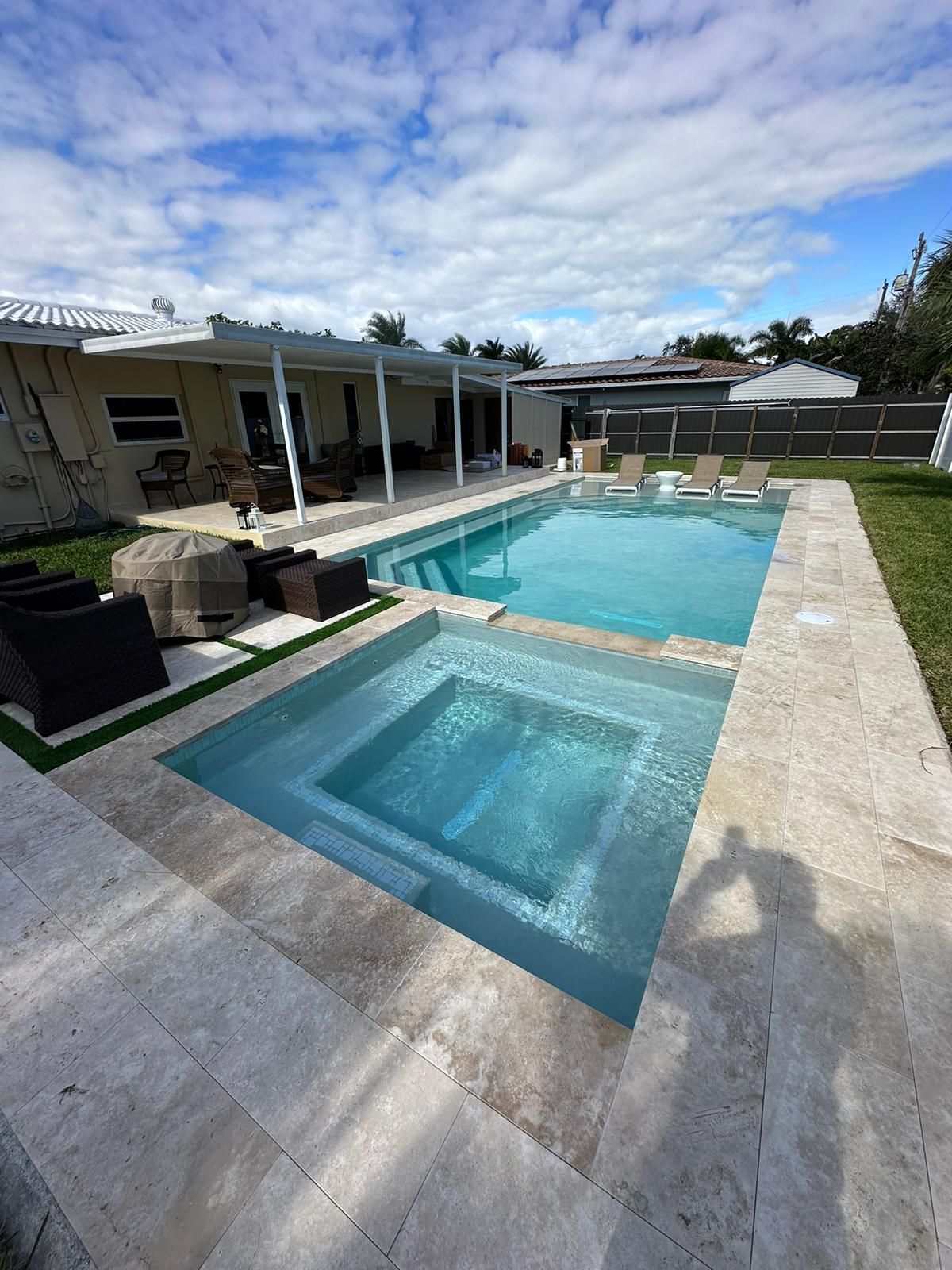A large swimming pool with a hot tub in the backyard of a house.