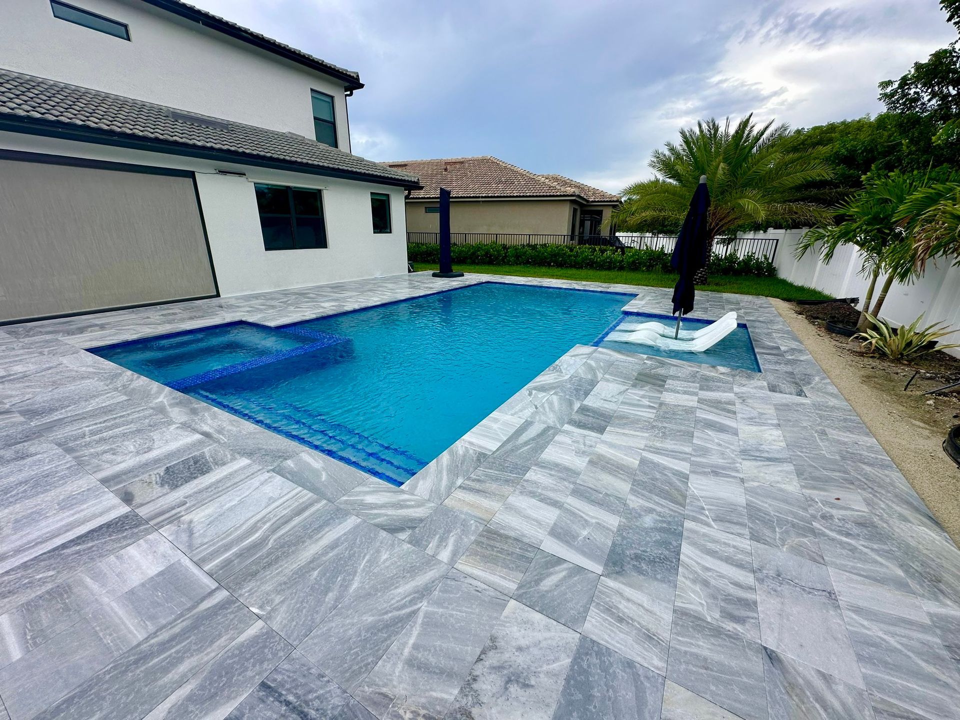 There is a large swimming pool in the backyard of a house.