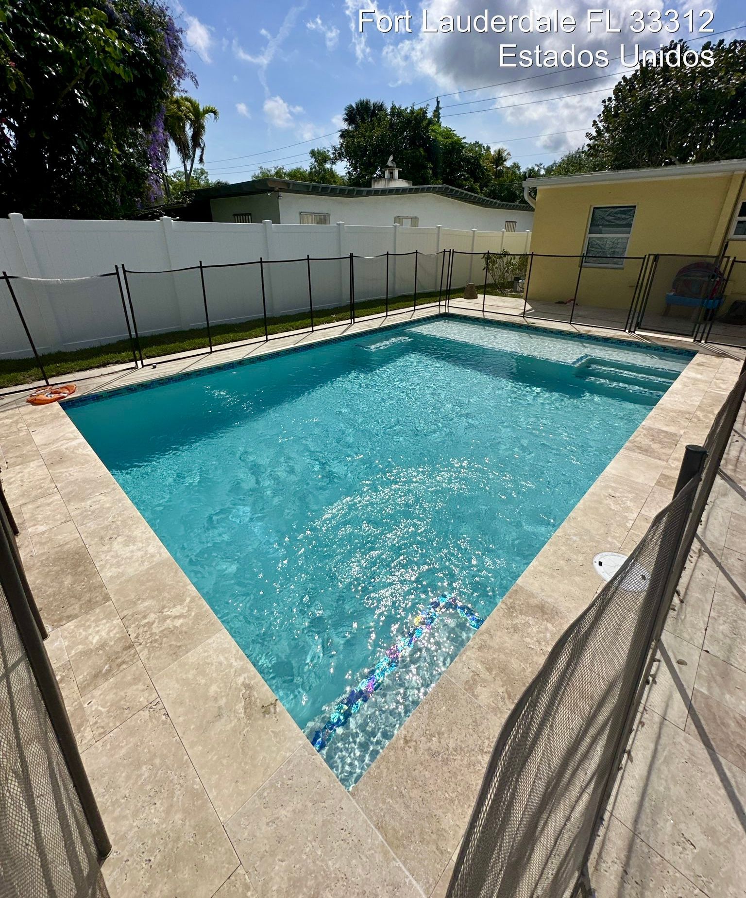 A large swimming pool is surrounded by a fence in a backyard.