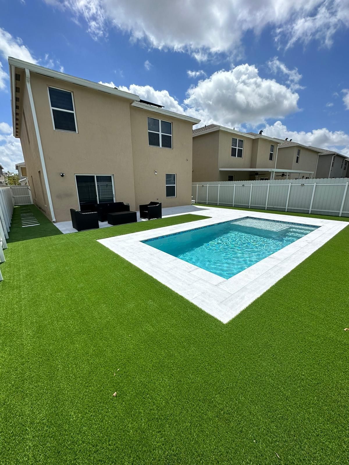 There is a large swimming pool in the backyard of a house.