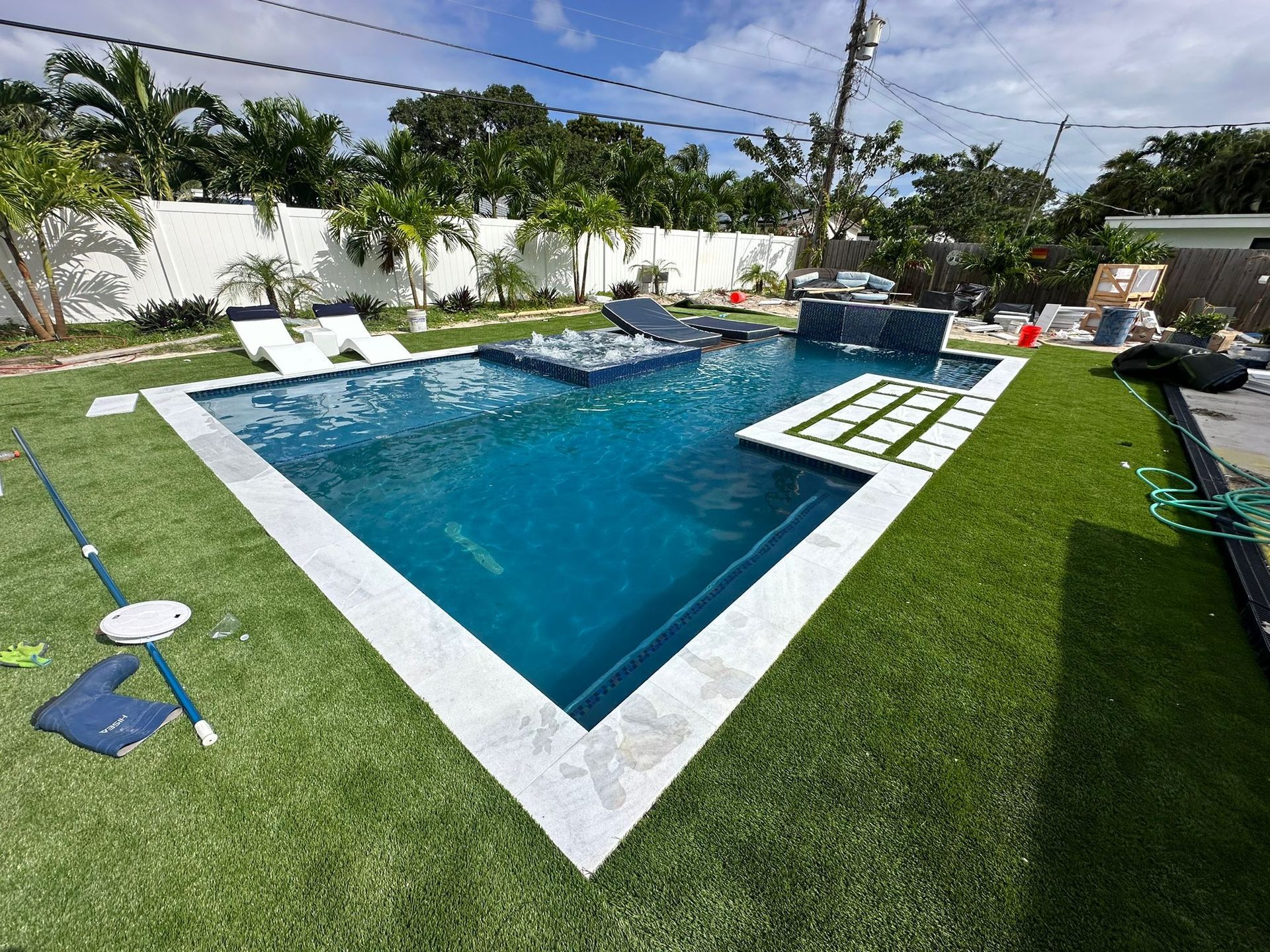 A large swimming pool is surrounded by a lush green lawn.