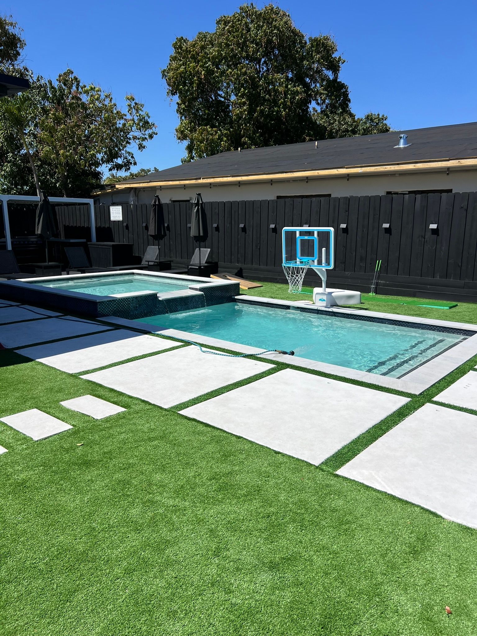 There is a large swimming pool in the backyard of a house.