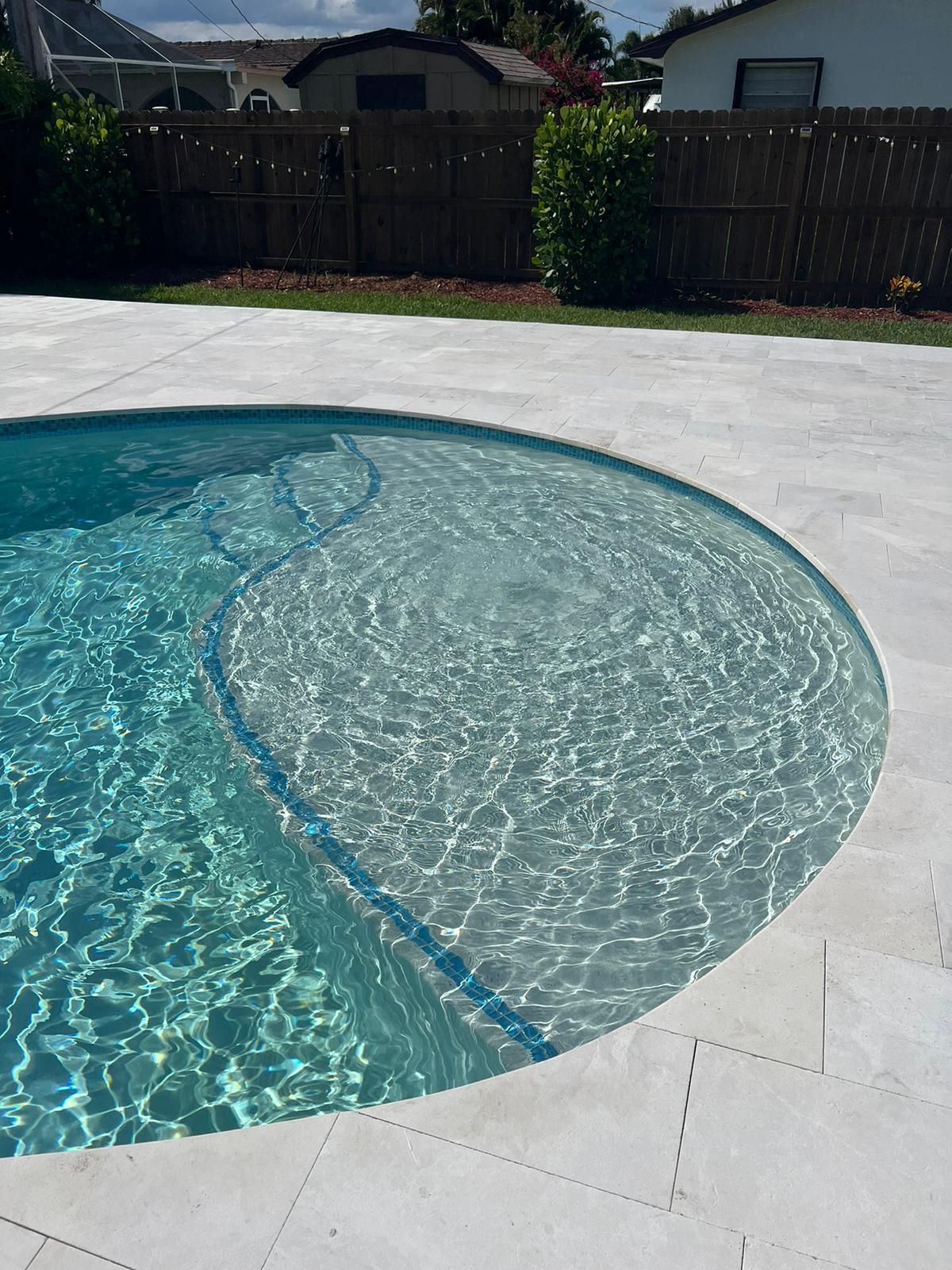 A swimming pool with a wooden fence in the background