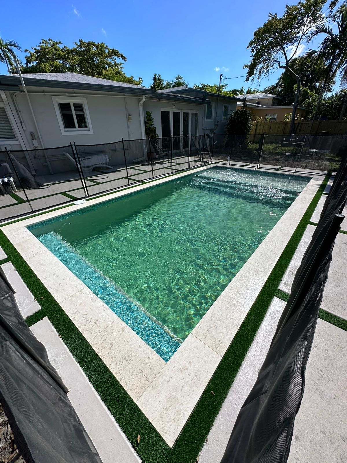 A large swimming pool in the backyard of a house.