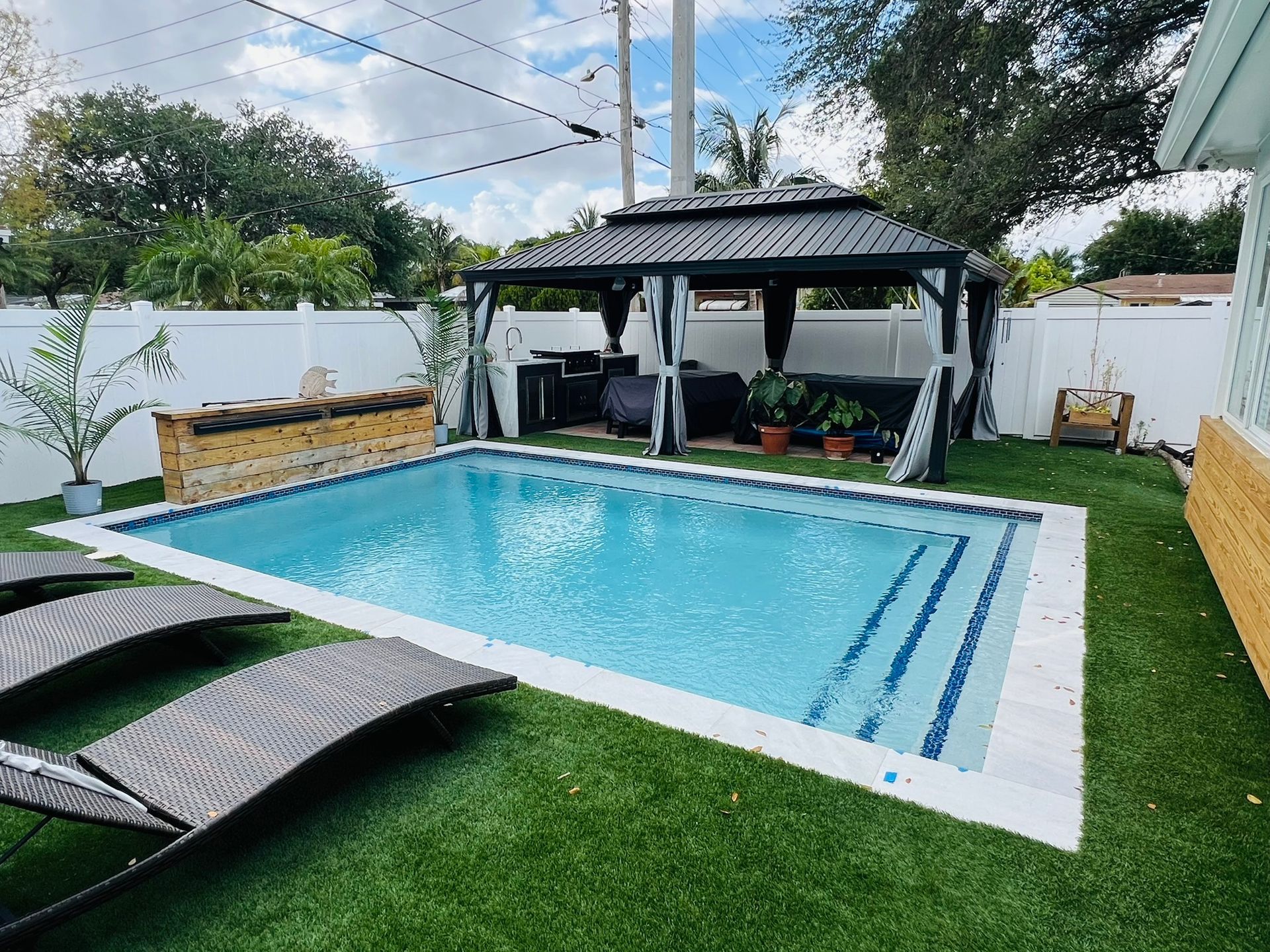 A large swimming pool with a gazebo in the backyard of a house.