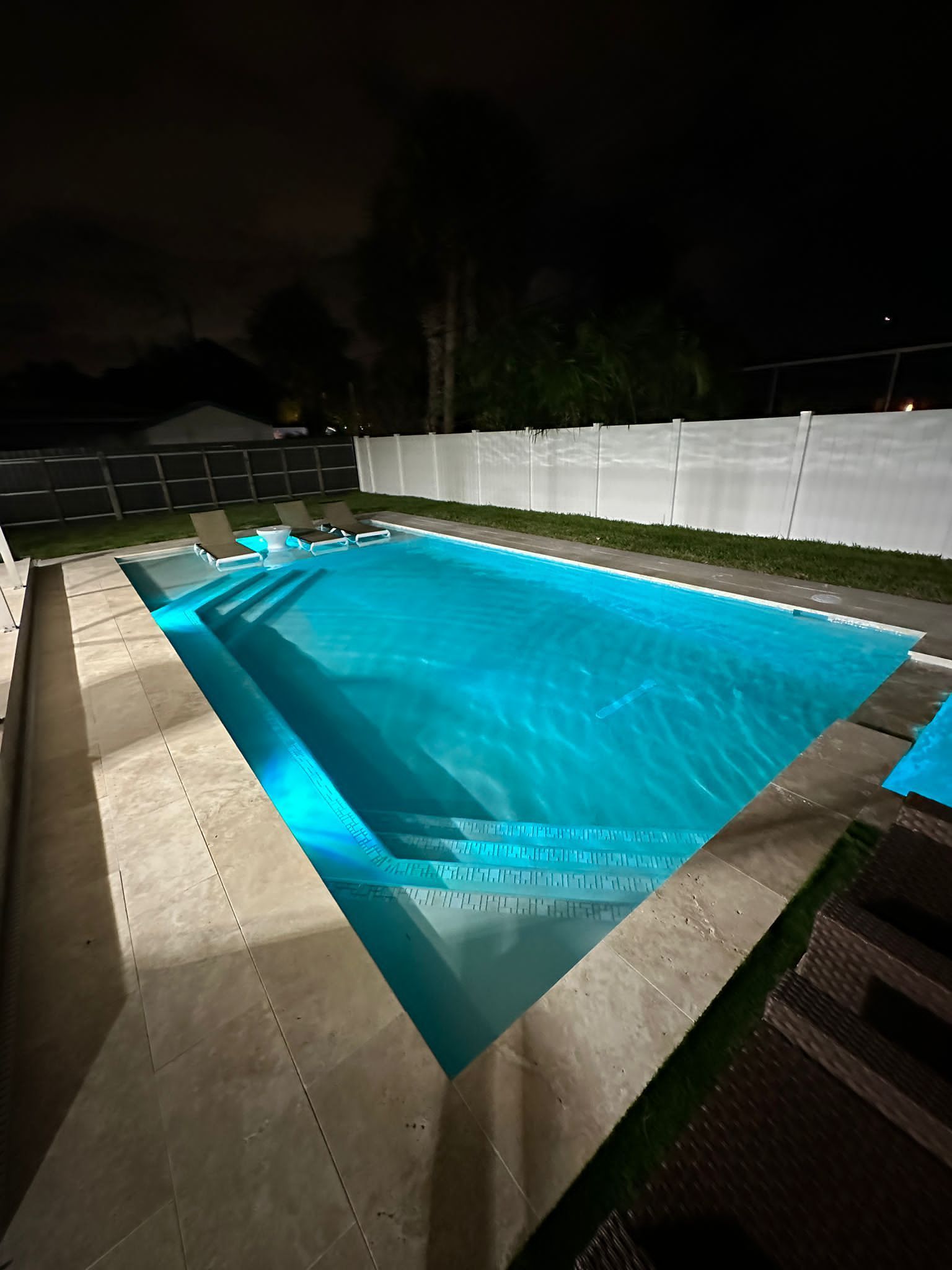 A large swimming pool is lit up at night.