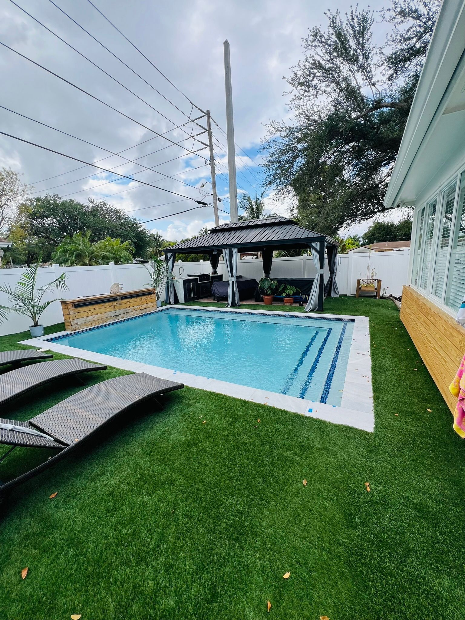 There is a large swimming pool in the backyard of a house.