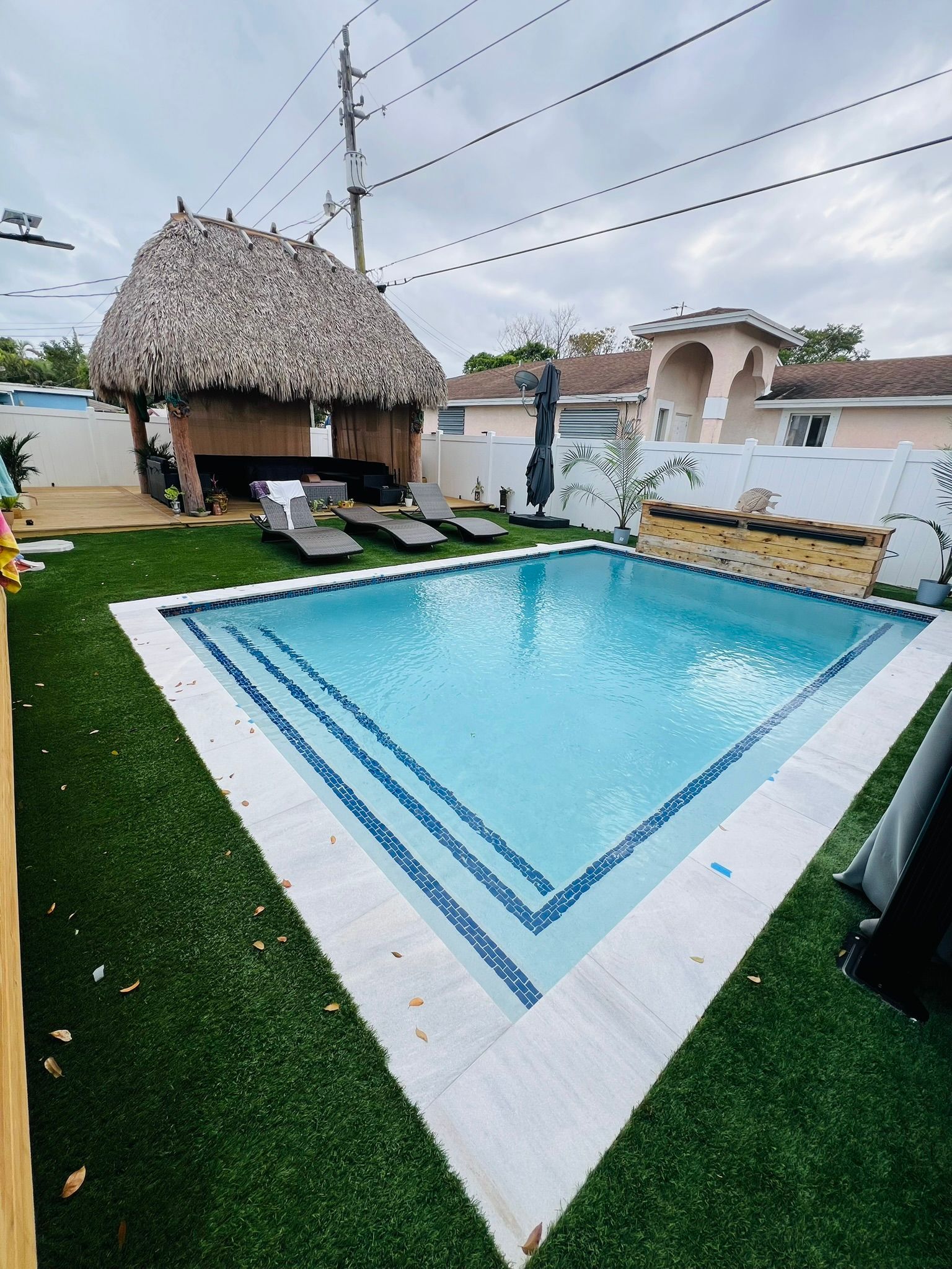 A large swimming pool with a thatched hut in the background.