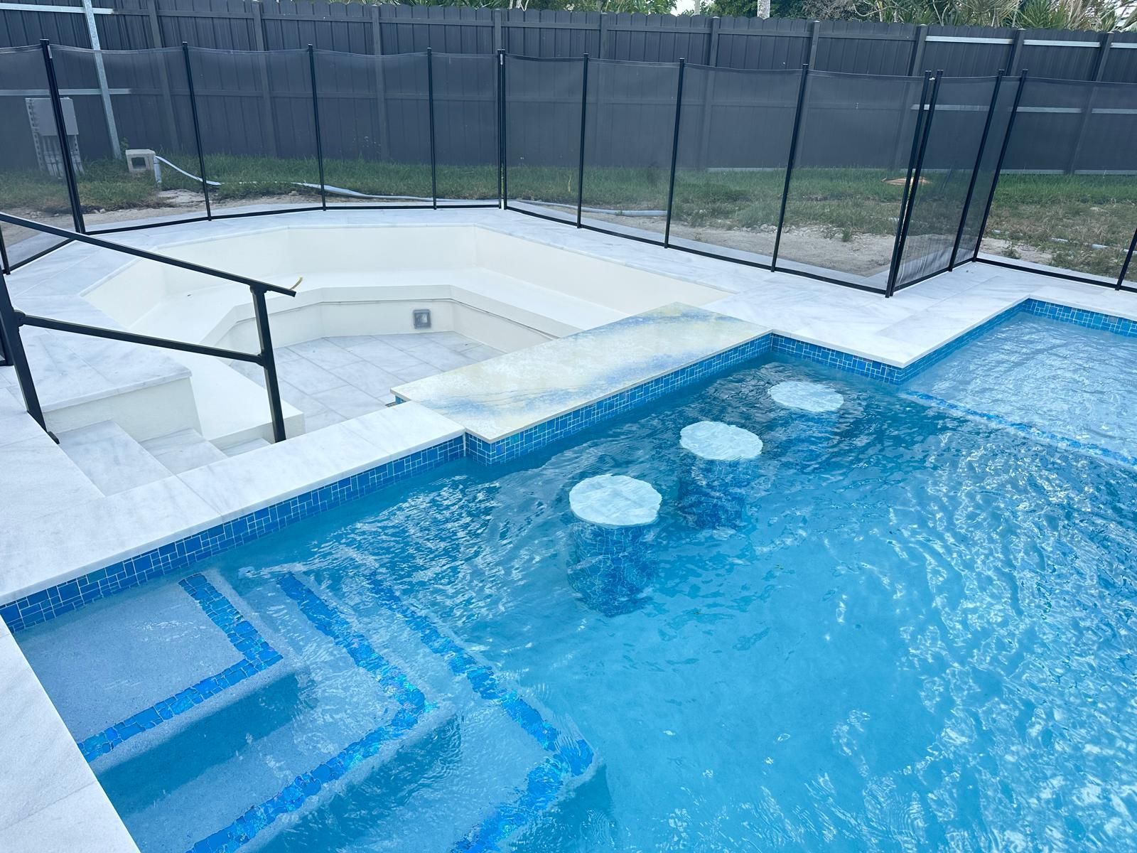 A large swimming pool with stairs and a fence around it.