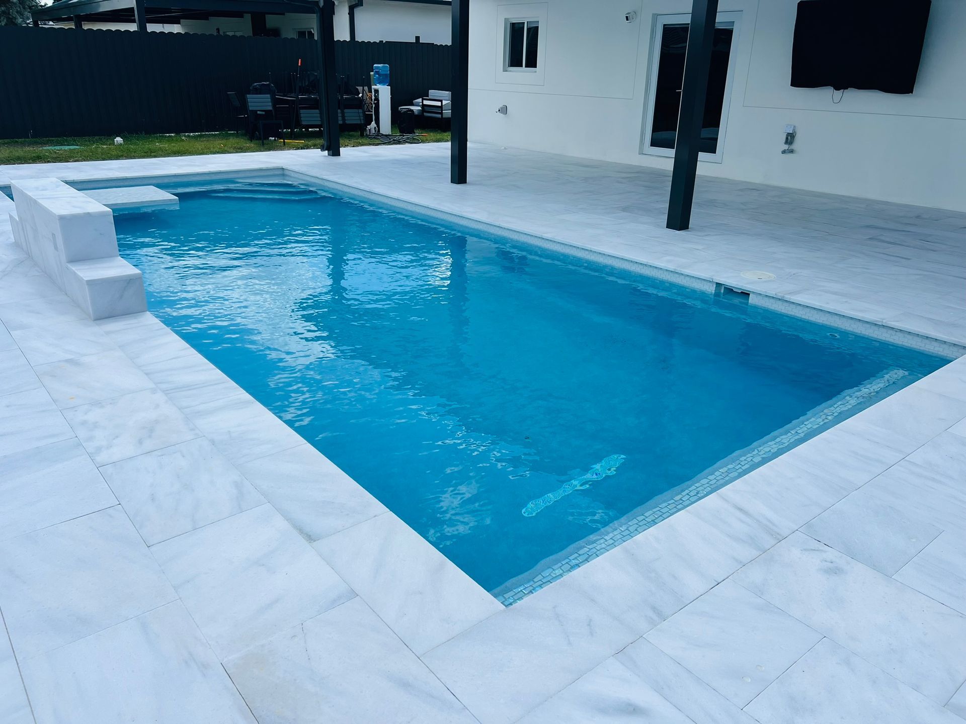 A large swimming pool is surrounded by white tiles
