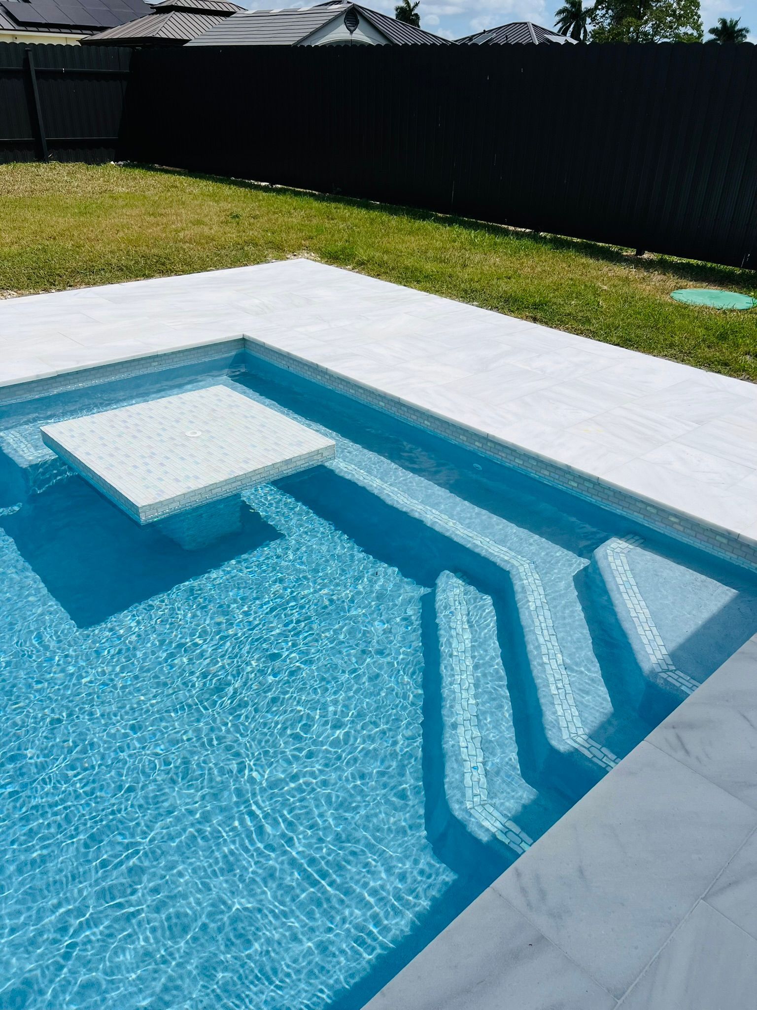 A large swimming pool with stairs and a table in the middle of it.