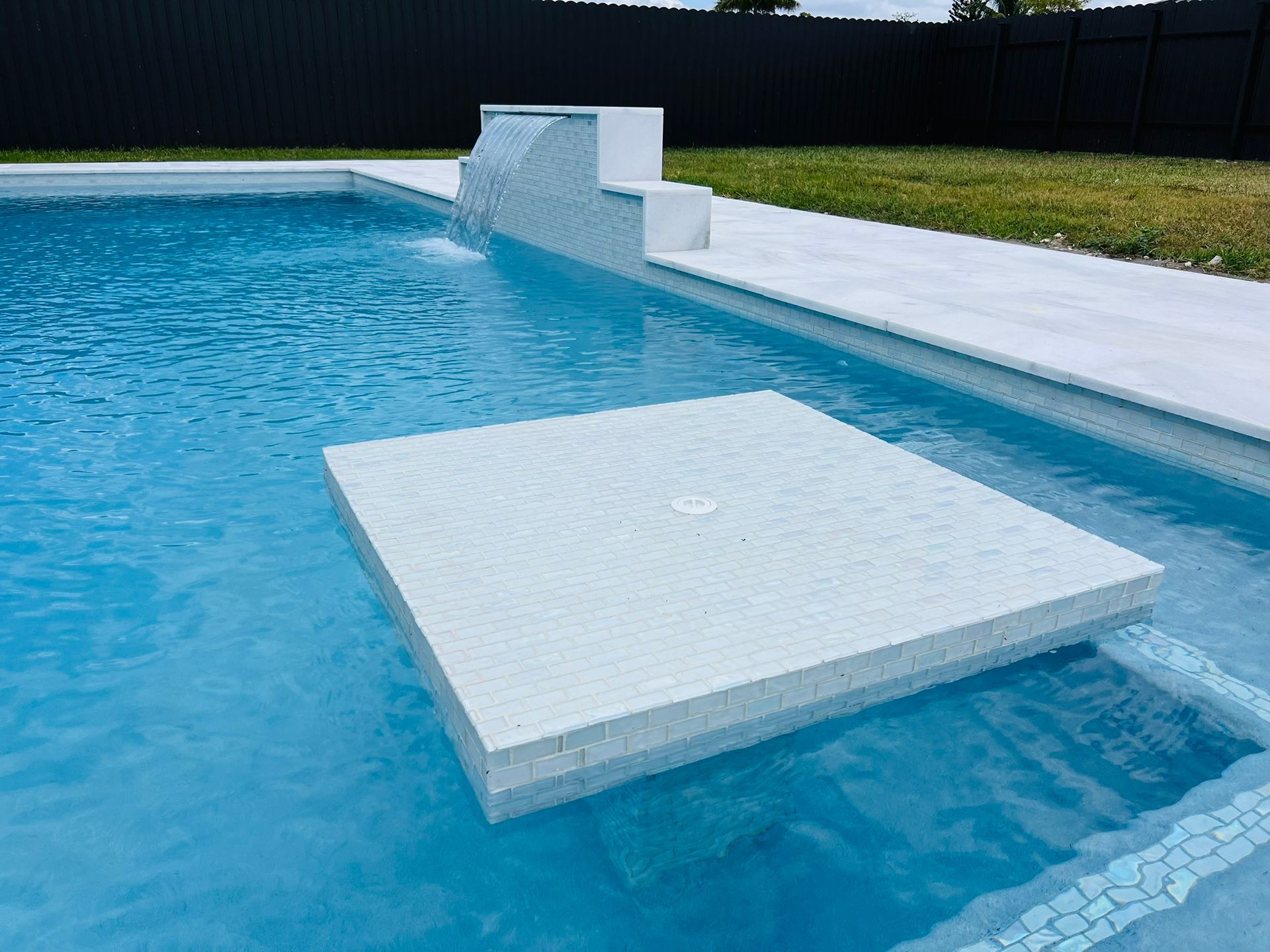 A swimming pool with a white platform in the middle of it.