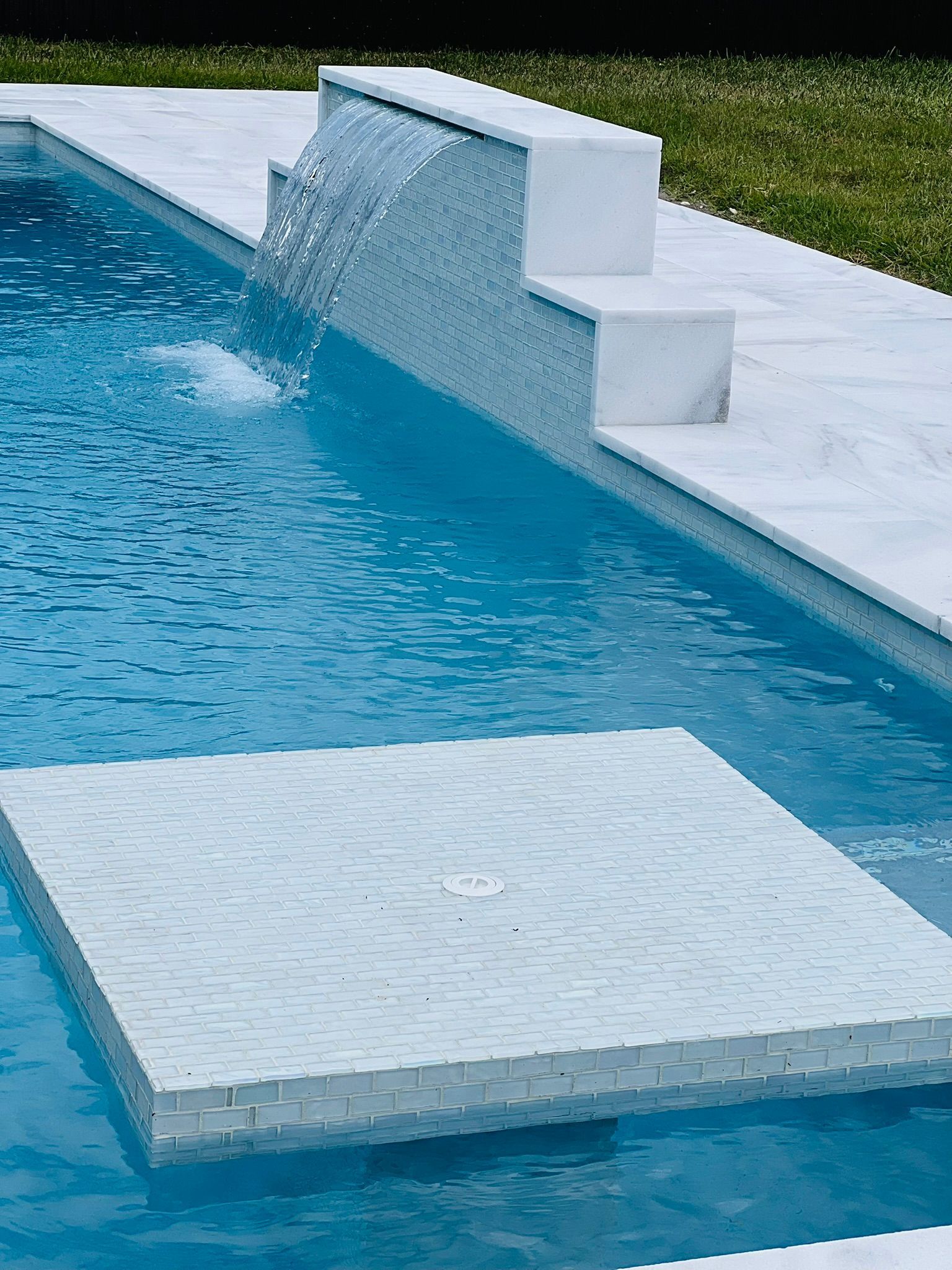 A swimming pool with a waterfall on the side of it